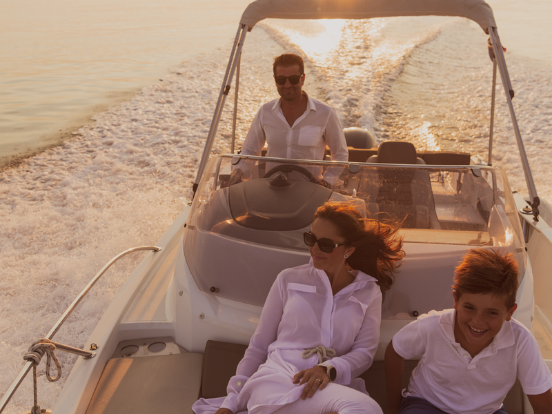 A senior couple in casual outfits with their son enjoy while riding a boat at sea at sunset. The concept of a happy family. Selective focus