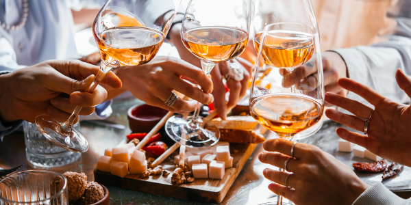 Friends having a dinner party with different kinds of appetizers and rose wine