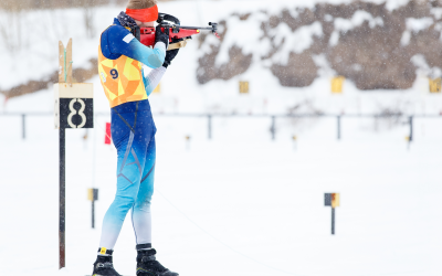 Tiro de atleta em posição de pé no intervalo em uma competição de biatlo.