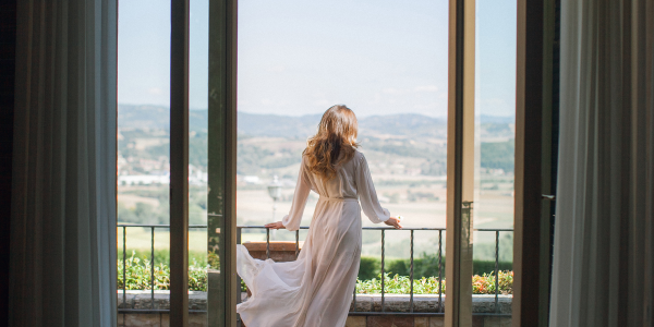 a noiva no boudoir casamento está de pé na varanda e admirando a Itália solar